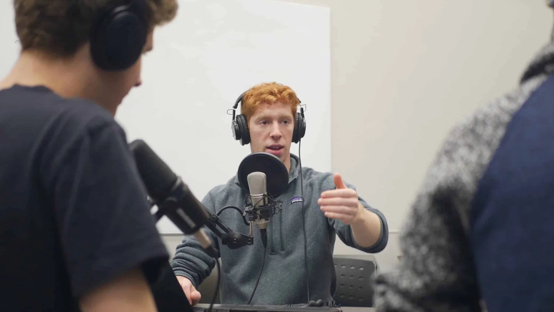 A Beyond ME co-host gesturing while speaking into a studio microphone