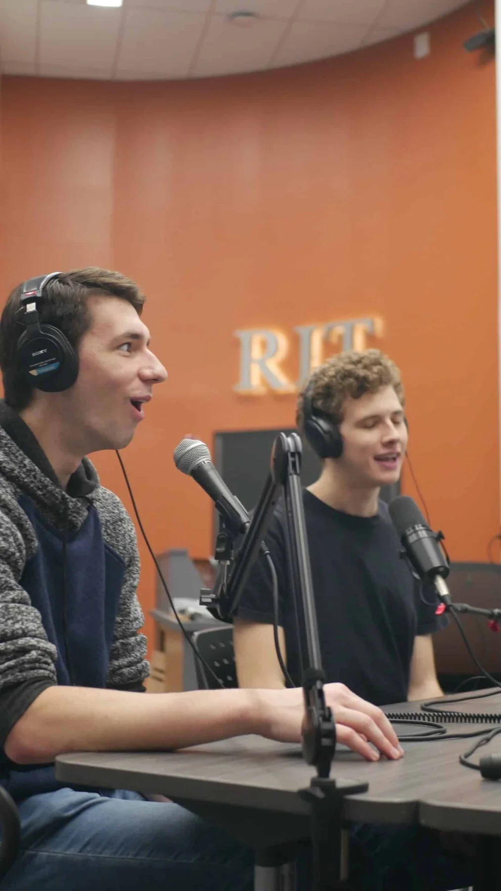 Two Beyond ME co-hosts speaking into microphones in an RIT studio